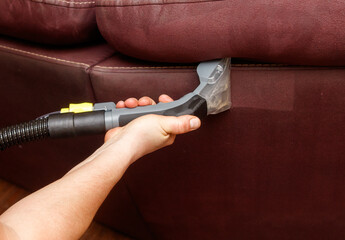 A person is cleaning a couch with a vacuum