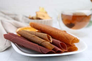 Tasty fruit leather rolls on white table, closeup