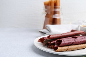 Tasty fruit leather rolls on white table, closeup. Space for text
