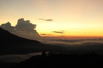 Picturesque view of mountains covered with fog on sunset