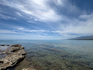 Rocky shore and clear water of Issyk-Kul under a vast sky