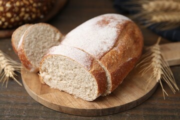 Fresh cut bread and spikes on wooden table, closeup
