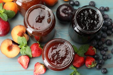 Different jams in jars and ingredients on blue wooden table, flat lay