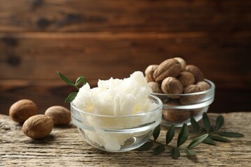 Natural shea butter, nuts and leaves on wooden table, closeup