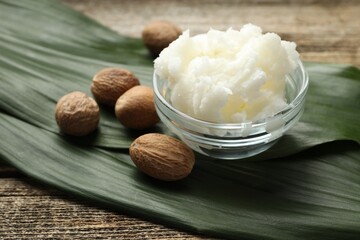 Natural shea butter and nuts on wooden table, closeup
