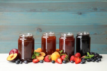 Different jams in jars and ingredients on white table. Space for text
