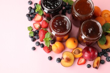 Different jams in jars and ingredients on light pink background, flat lay