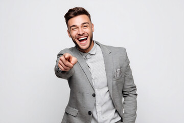 Young Russian man in business attire laughs while pointing at an unseen object against a white background
