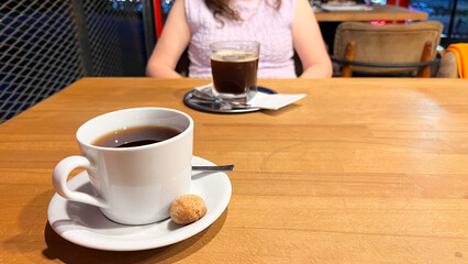 Coffee served in a porcelain cup on a wooden table in a café.