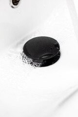 This is a closeup picture capturing a sink drain with water flowing out of it