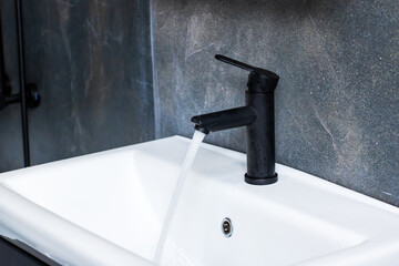 A sleek black faucet is elegantly pouring water into a white sink