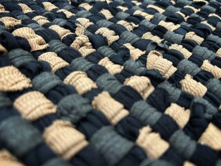 A close-up photo of a woven fabric surface with a checkered pattern. It consists of tightly...