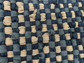 A close-up photo of a woven fabric surface with a checkered pattern. It consists of tightly...