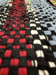 A close-up photo of a woven fabric surface with a checkered pattern. It consists of tightly...