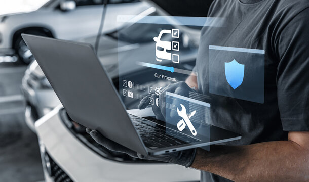 Mechanic using laptop checking up on car engines parts for fixing and repair. - Powered by Adobe