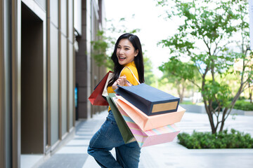 Fototapeta premium Portrait of Asian woman shopping goods outdoors in department store. 