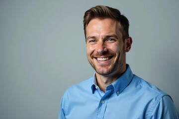 Blue-shirted executive smiling, isolated gray backdrop, management, photography