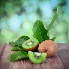 Kiwi fruits with leaves on wooden table.