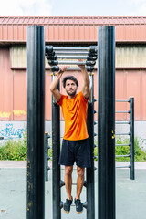 Determined athlete performing hanging leg raises on outdoor exercise equipment