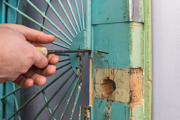 Closeup of man chiseling groove in door leaf for lock installation. Worker carving out door frame with tool, preparing area for lock replacement