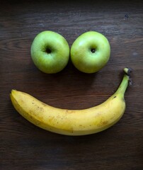 banana and two green apple on dark wooden background 