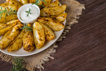 Baked new potatoes with spices and creamy sauce in a plate on a wooden table