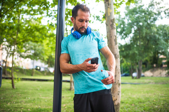Handsome male athlete checking his phone after outdoor training