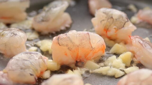 Seared raw shrimp and garlic on a hot frying pan. Close up shot