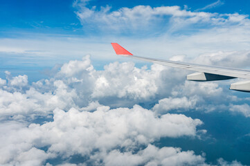 The wing of an airplane on the background of clouds in flight. A clear day