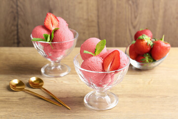 Refreshing sorbet, strawberries, mint and spoons on wooden table, closeup