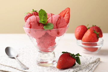 Refreshing sorbet with syrup, strawberries and mint in dessert bowl on white table against beige background, closeup