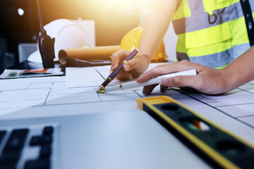 Closeup of team of industrial engineers meeting analyze machinery blueprints consult project on table in manufacturing factory. Working in manufacturing plant or production plant.