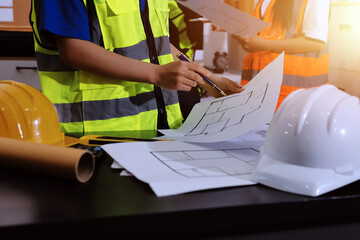 Closeup of team of industrial engineers meeting analyze machinery blueprints consult project on table in manufacturing factory. Working in manufacturing plant or production plant.