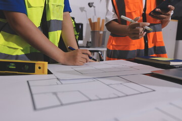 Closeup of team of industrial engineers meeting analyze machinery blueprints consult project on table in manufacturing factory. Working in manufacturing plant or production plant.