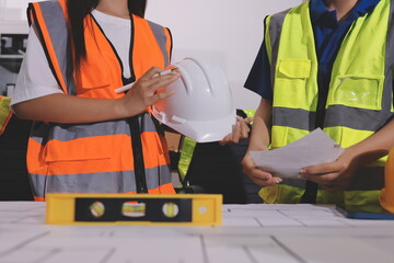 Closeup of team of industrial engineers meeting analyze machinery blueprints consult project on table in manufacturing factory. Working in manufacturing plant or production plant.