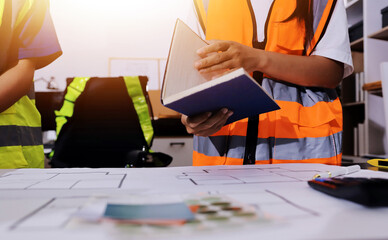 Closeup of team of industrial engineers meeting analyze machinery blueprints consult project on table in manufacturing factory. Working in manufacturing plant or production plant.