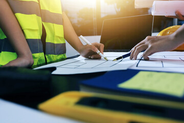 Closeup of team of industrial engineers meeting analyze machinery blueprints consult project on table in manufacturing factory. Working in manufacturing plant or production plant.