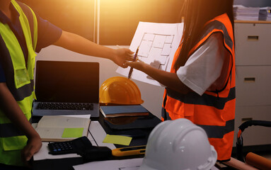 Closeup of team of industrial engineers meeting analyze machinery blueprints consult project on table in manufacturing factory. Working in manufacturing plant or production plant.