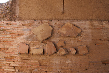Ancient brick wall with variously shaped terracotta fragments attached, showcasing historical...