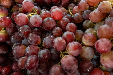 Close-up of fresh red grapes with a natural bloom on the skin, arranged in a tight cluster. The image highlights texture, freshness, and vibrant color, ideal for food concepts.