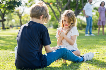 Fototapeta premium Brother and sister playing together at the park in the morning sunrise