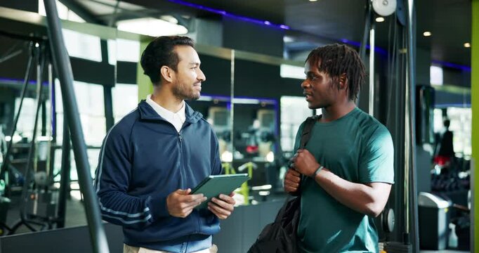 Conversation, man and personal trainer with tablet in club for planning of training program. App, consulting or exercise with client and fitness coach in gym for development of workout schedule