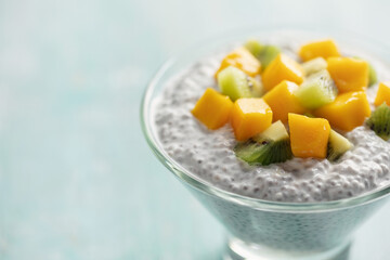 Chia seed pudding from coconut milk with mango cubes and kiwi fruit  in glass bowl. Vegan  food. Clean eating concept
