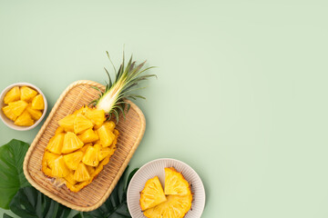 Fresh pineapple chunks served in a pineapple bowl on green table background.
