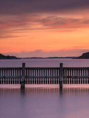 Obraz premium Coastal sunset reflecting on calm waters at harbour near Gothenburg in Sweden