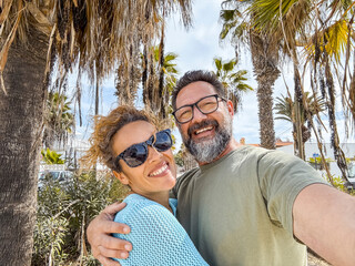 Naklejka na ściany i meble Happy middle aged couple have fun walking outdoors in the city. Couple enjoying a tourist walk on the street in spring. Tourist couple relationships and newlyweds' holidays.
