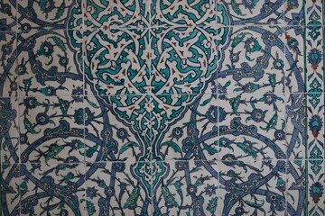 Elegant Islamic ceramic tiles with a symmetrical floral and arabesque design in turquoise, navy blue, and white, forming a stylized tree-like motif.