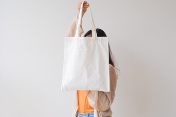 Woman holding canvas tote bag on white background. Reusable eco bag for shopping. Eco friendly concept. Mockup for design.