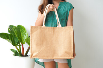 Woman holding  jute bag or sack bag on white background. Reusable shopping bag. Natural material. Zero waste. Plastic free. Eco friendly concept.