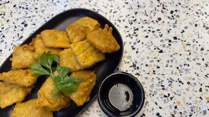 A plate of freshly fried Tempe Mendoan, a popular Indonesian snack made from thinly sliced tempeh...